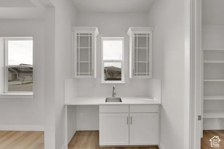 Built-in wet bar featuring a stainless steel sink, white cabinetry, and white tile backsplash