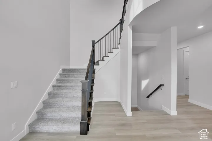 Carpeted staircase featuring a dark wood newel post and wrought iron balusters