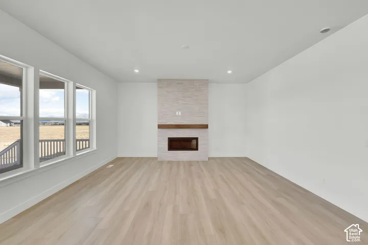 Living area with wood-finish flooring, recessed lighting, a fireplace with a wood mantel, and multiple windows