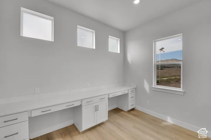 Integrated desk with white cabinetry, white countertops, and sleek hardware
