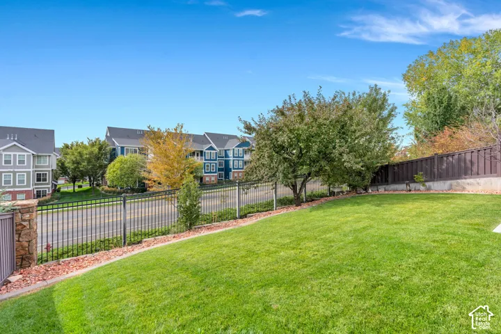 Expansive lawn area, mature trees, wood fence, and a decorative stone column