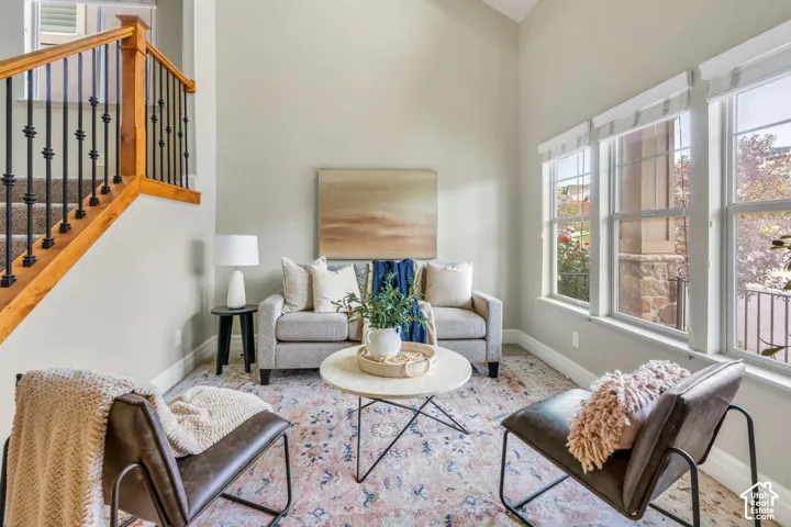Vaulted ceiling, multiple windows, staircase with wood handrail and wrought iron spindles, recessed lighting, and wall-to-wall carpeting