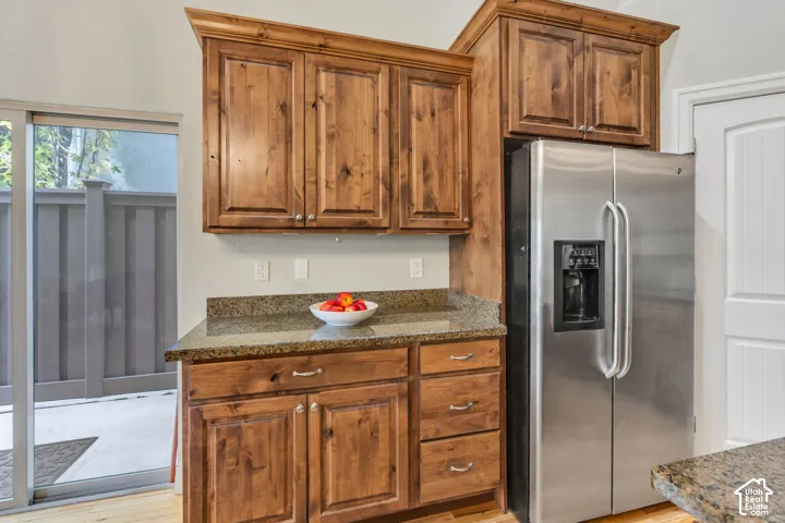 Open concept living space featuring vaulted ceilings, wood-finish flooring, kitchen island with built-in sink, stainless steel appliances, and updated light fixtures and updated chandelier. Wood cabinets and granite countertops and an exterior sliding gla