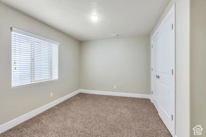 Basement Bedroom with Recessed lighting, neutral wall tones, window with horizontal blinds, bi-fold closet doors, and plush carpet flooring
