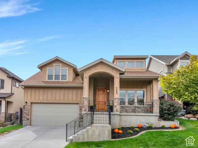 Two-story residence featuring a covered front entry with stone columns, a covered porch with iron railing, and a multi-pane front door