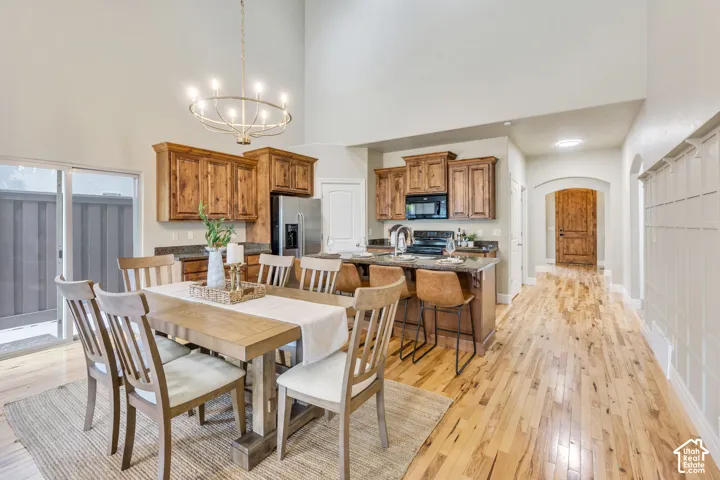 Vaulted ceiling with chandelier, wood-finish flooring, kitchen island with built-in sink, wood cabinetry, and sliding glass door