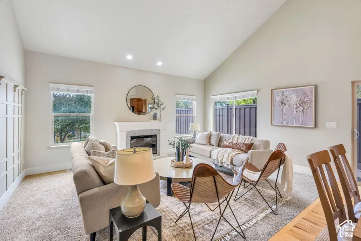 Vaulted ceiling, decorative wall paneling,  fireplace, recessed lighting, and large windows providing natural light.