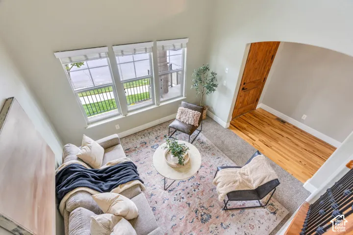 Vaulted ceiling with three tall windows, light wood-finish flooring, and an arched doorway