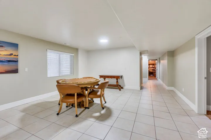 Spacious home gym or game room featuring light-colored floor tiling, recessed lighting, and multiple windows with blinds