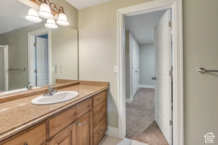 Jack and Jill Bathroom for 2 basement bedrooms with Warm-toned vanity with an integrated sink, polished chrome faucet, and expansive wall mirror