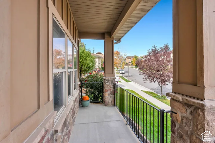 Covered porch with stone accents, concrete flooring, and black metal railing