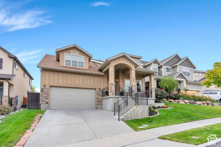 Craftsman-style 2 story HOME with stone accents, covered front porch, attached garage, dormer windows, and mature trees.