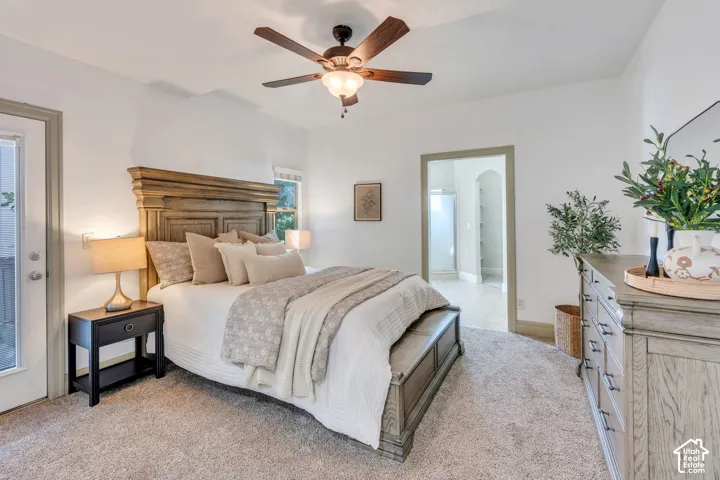 Main Level Primary Bedroom with carpet, a ceiling fan, and a glass-paneled exterior door that opens to a private covered patio. A peaceful retreat just outside your bedroom.