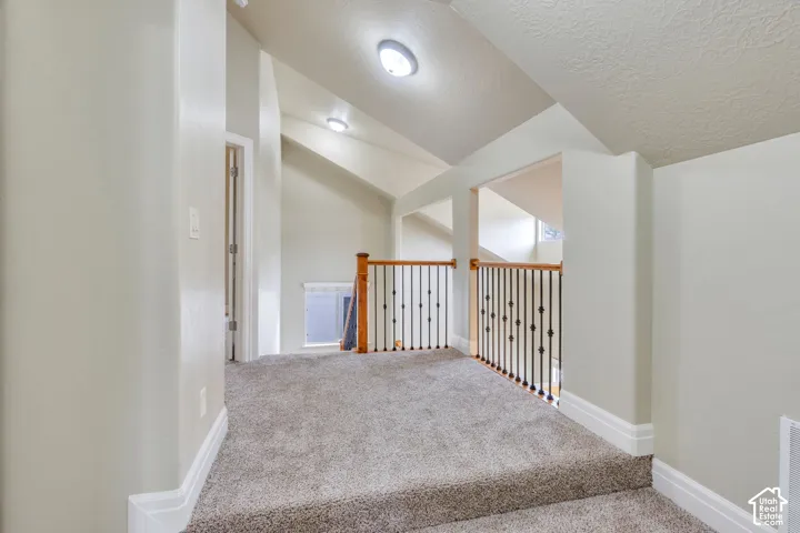 2nd level hallway with vaulted ceilings, recessed lighting, carpeted flooring, and a wood handrail with wrought iron balusters