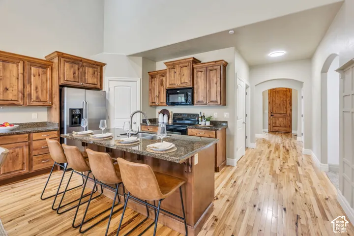 Open concept living space featuring vaulted ceilings, wood-finish flooring, kitchen island with built-in sink, stainless steel appliances, and updated light fixtures and updated chandelier. Wood cabinets and granite countertops