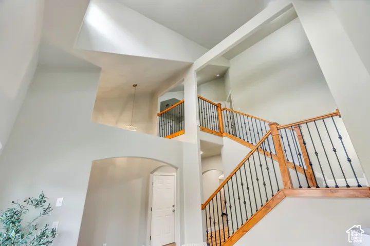 Two-story living room and foyer with a grand staircase featuring wood handrails and wrought iron balusters
