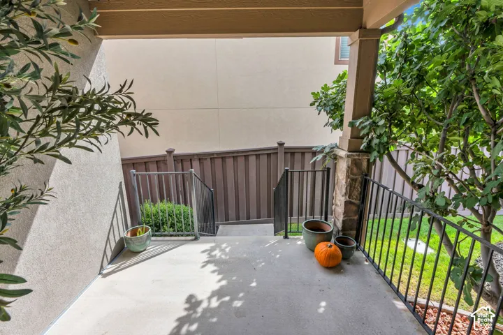 Your own private covered patio. A peaceful retreat just outside your bedroom. Outdoor patio with concrete flooring, black metal railings, and a privacy fence