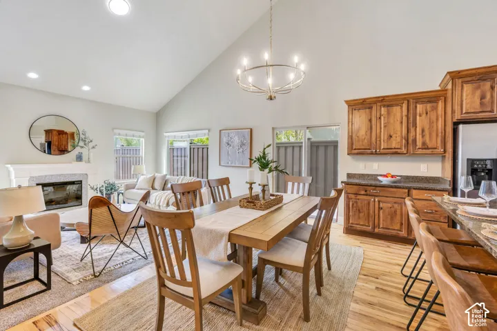 Open concept living space featuring vaulted ceilings, wood-finish flooring, kitchen island with built-in sink, stainless steel appliances, and updated light fixtures and updated chandelier. Wood cabinets and granite countertops