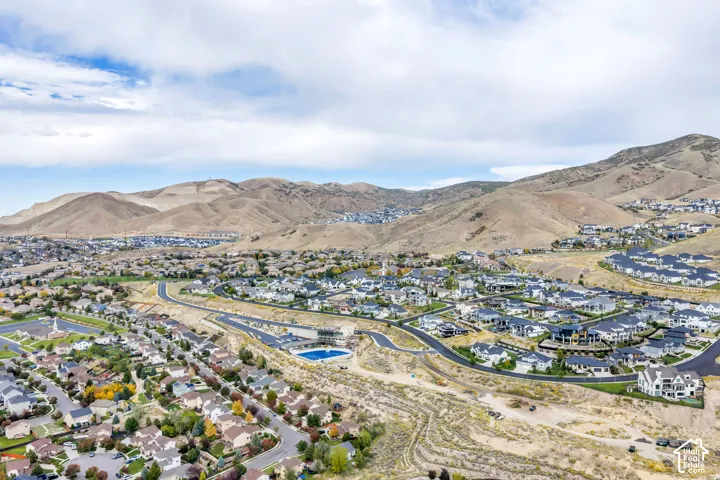 Expansive residential development nestled within a mountainous landscape, featuring a community swimming pool and curvilinear roadways