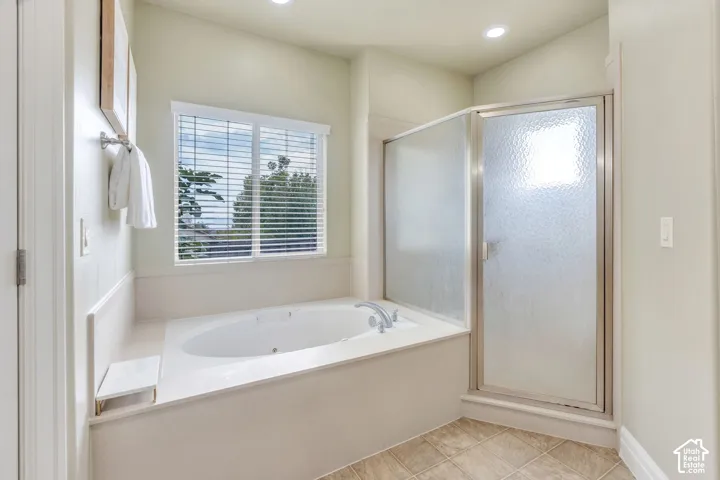 Main level primary bathroom features a double sink vanity with wood cabinetry, a separate shower, a relaxing soaking tub, and an adjoining primary closet.