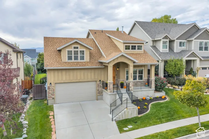 Craftsman-style 2 story HOME with stone accents, covered front porch, attached garage, dormer windows, and mature trees.
