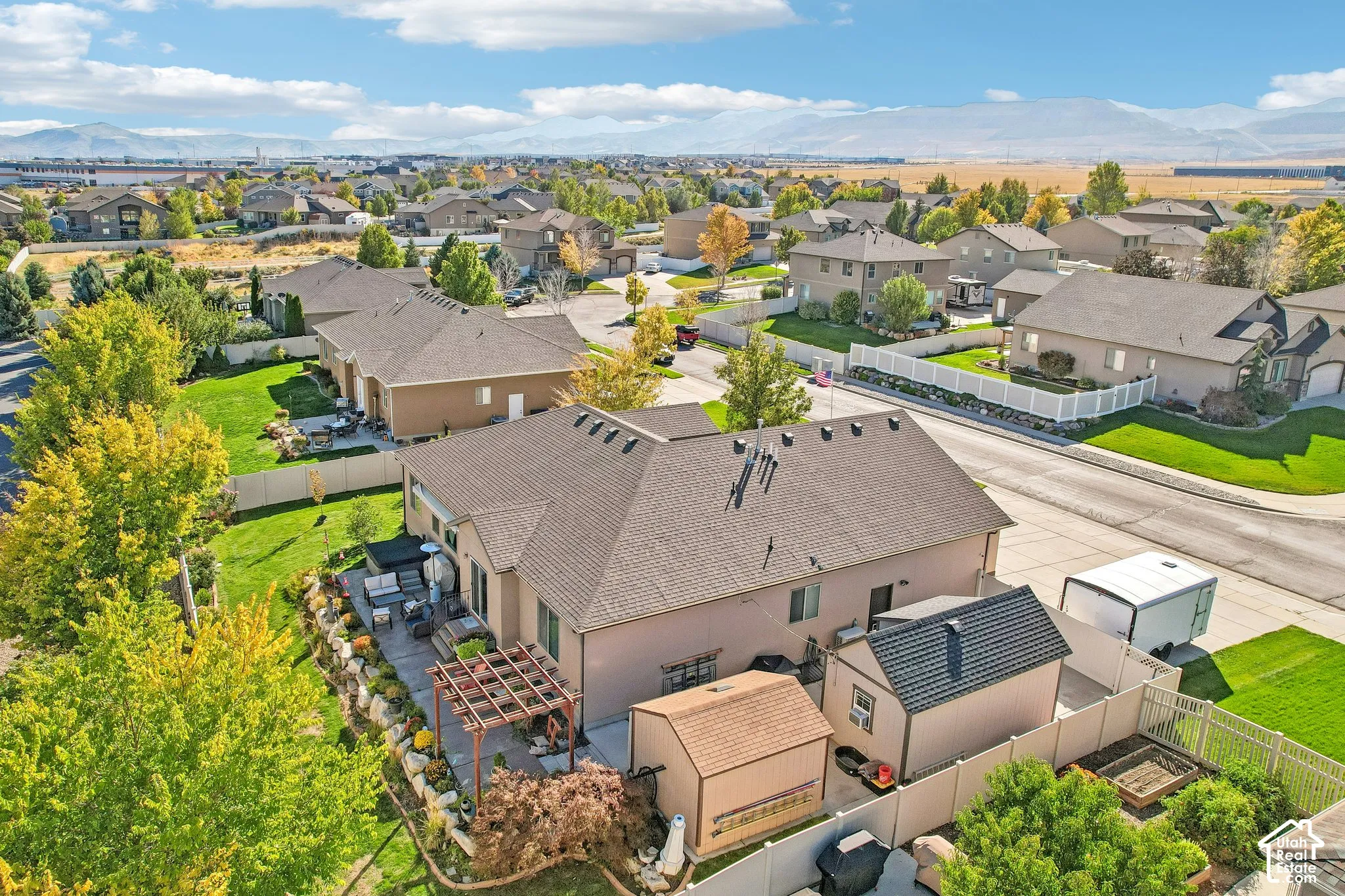 Expansive backyard featuring a pergola-covered patio, mature trees, and a manicured lawn