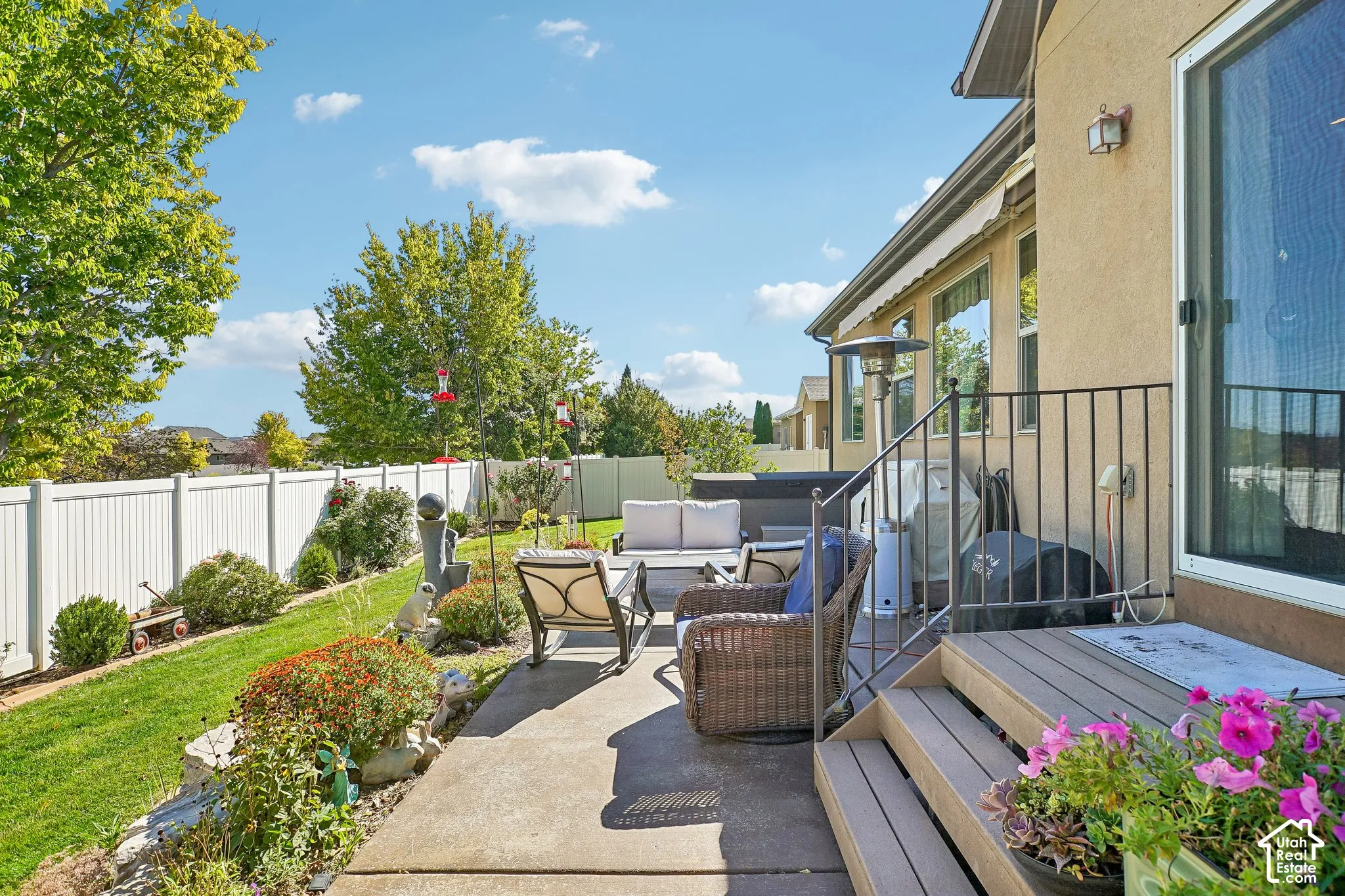 Backyard patio with concrete and composite wood decking, black metal railings, and a white privacy fence