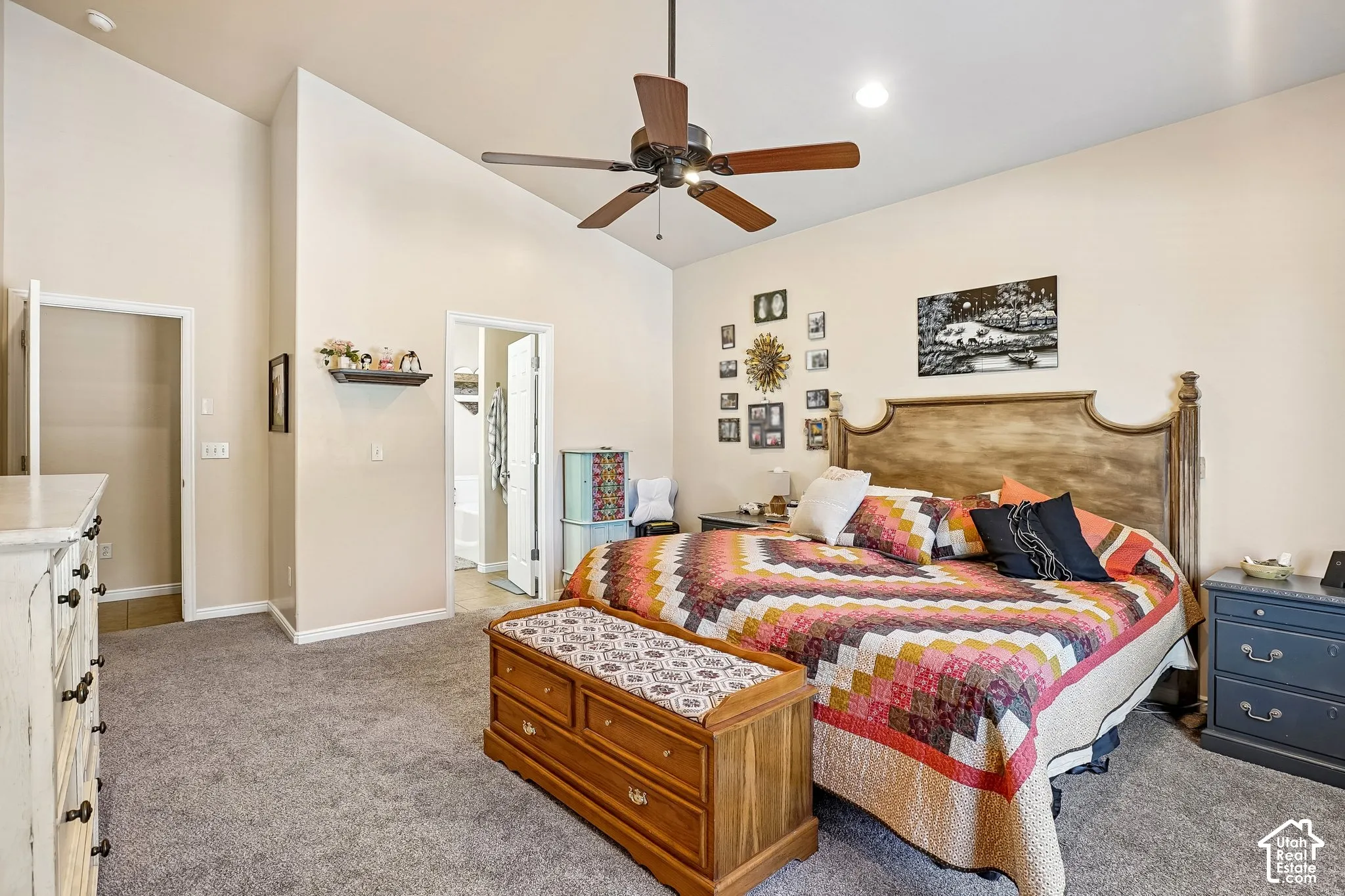 Vaulted ceiling with a ceiling fan, light neutral wall tones, and gray carpeting