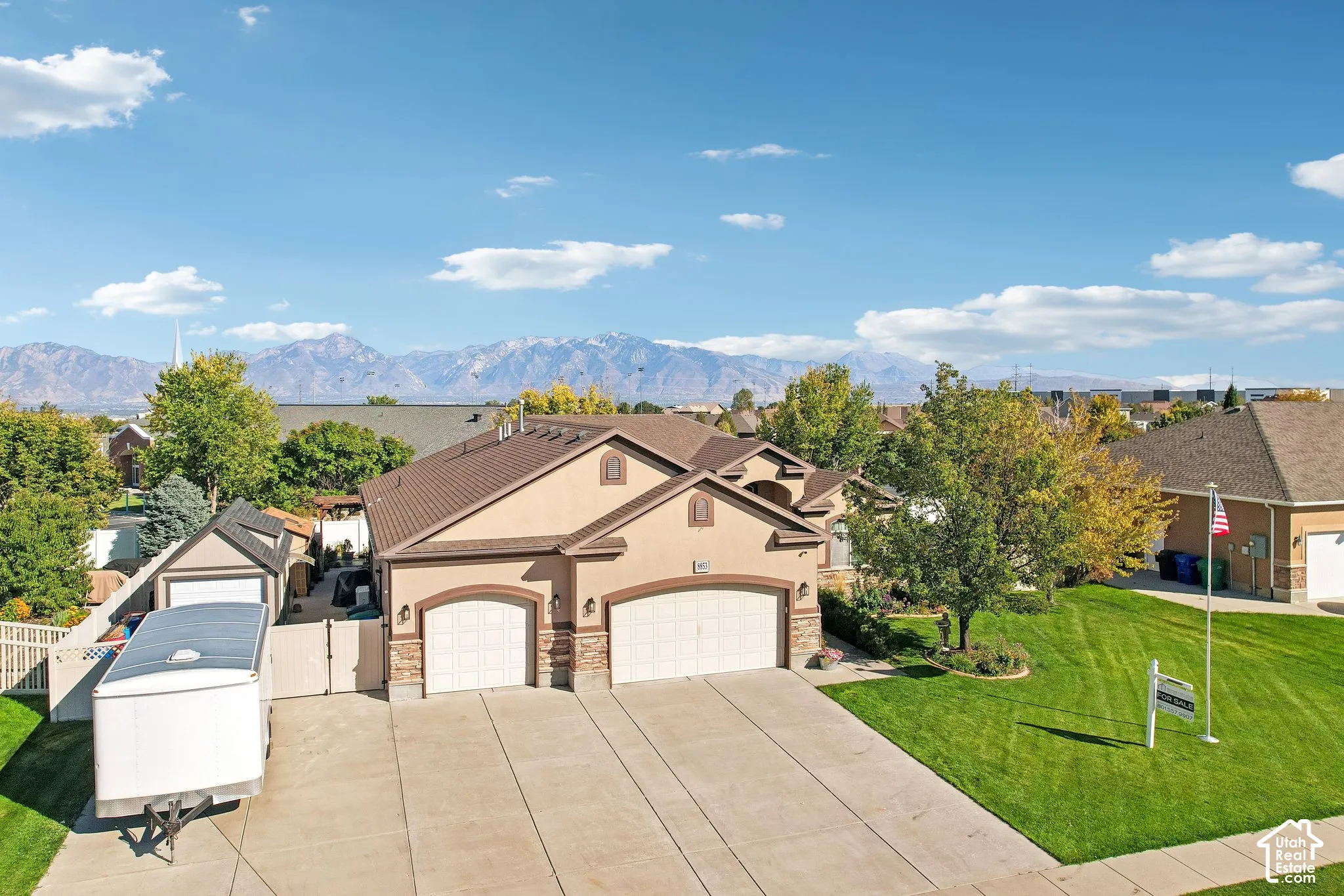 Stucco exterior with stone accents, two-car garage, concrete driveway, and a fenced yard with a gate