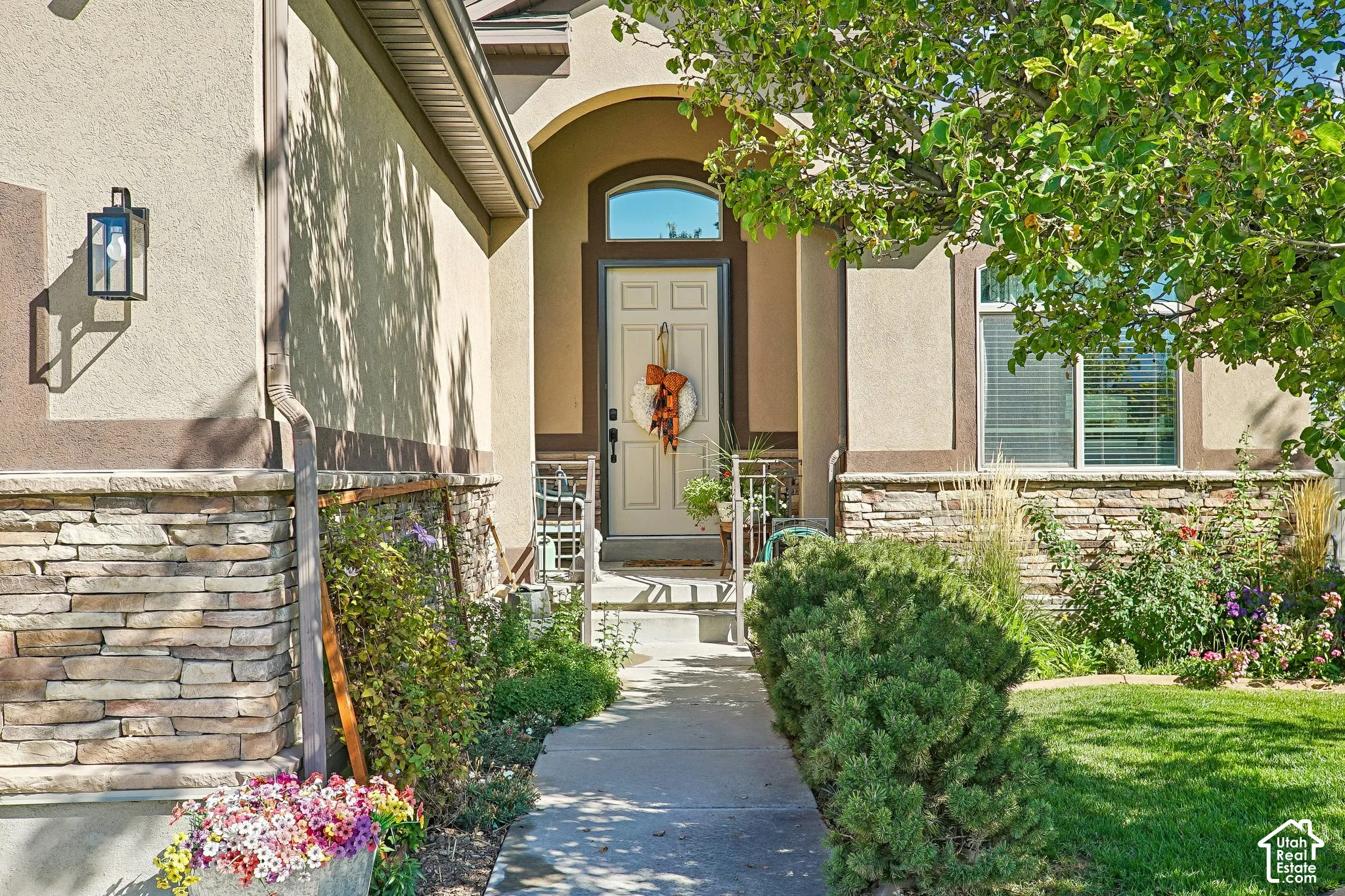 Stucco exterior with stone veneer accents, arched entry, transom window, and a concrete pathway