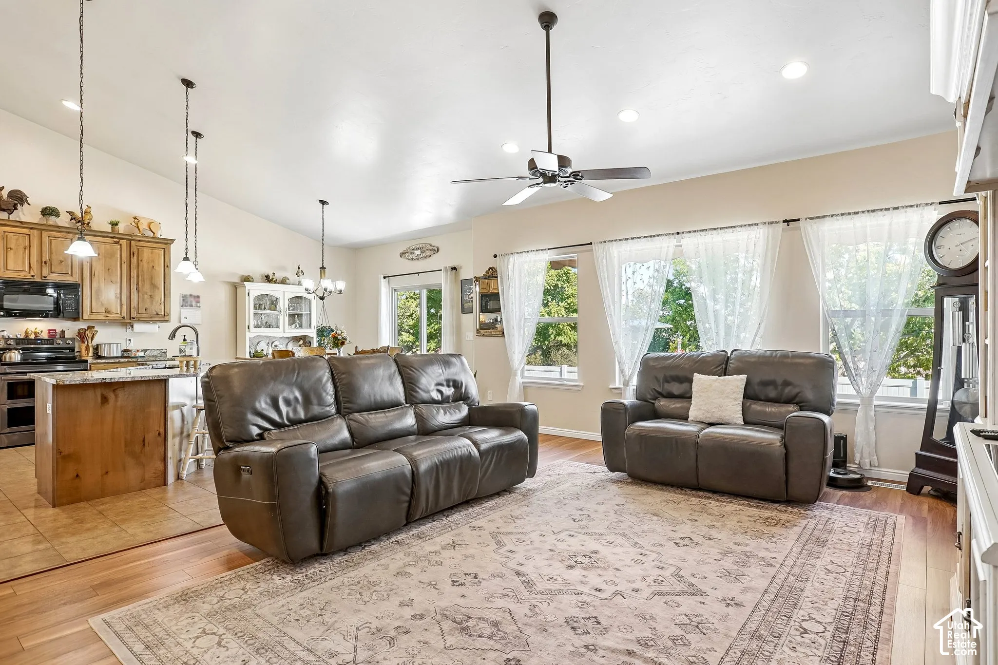 Vaulted ceiling with a ceiling fan, hardwood flooring, recessed lighting, and kitchen with wood cabinetry