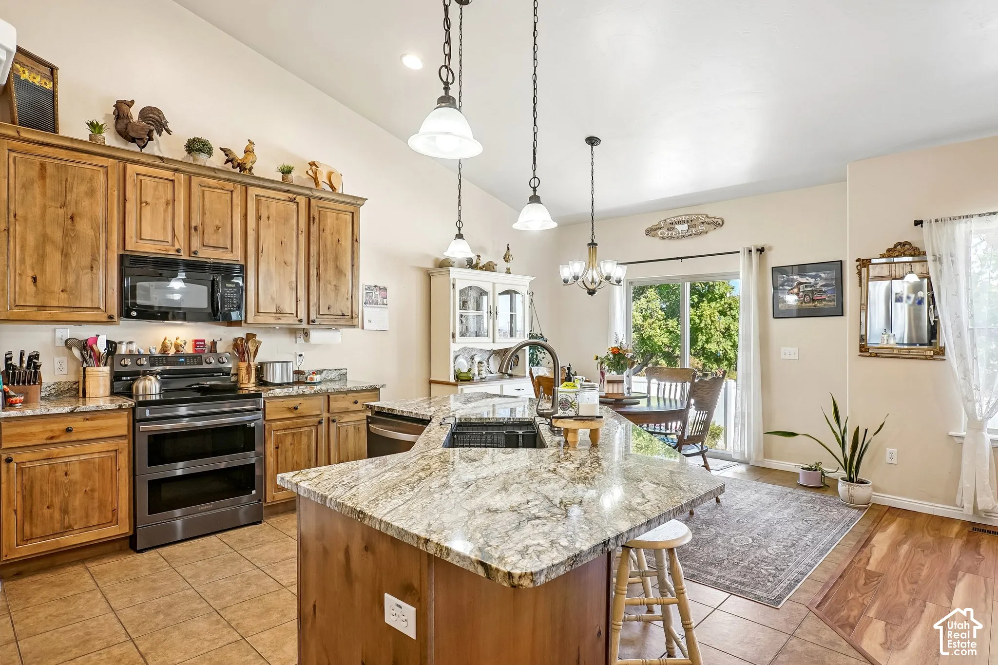 Kitchen featuring wood cabinetry, granite countertops, stainless steel appliances, and a central island with pendant lighting