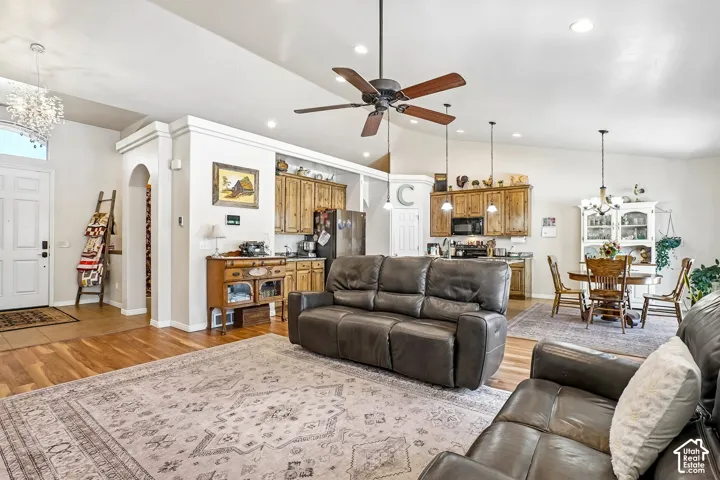 Open-concept living space with vaulted ceilings, wood-finish flooring, recessed lighting, and a ceiling fan