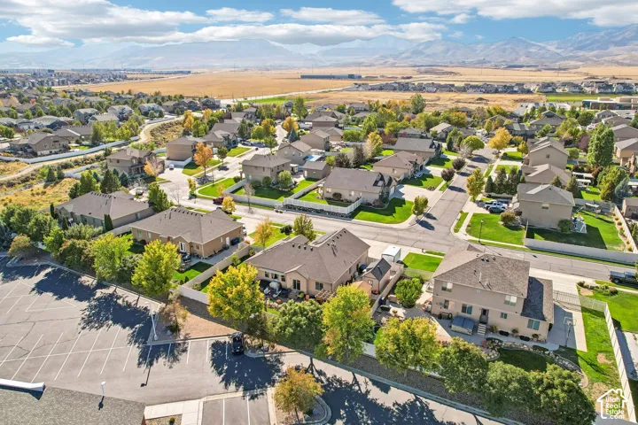 Residential neighborhood with paved streets and sidewalks, mature landscaping, varied architectural styles, and distant mountain backdrop