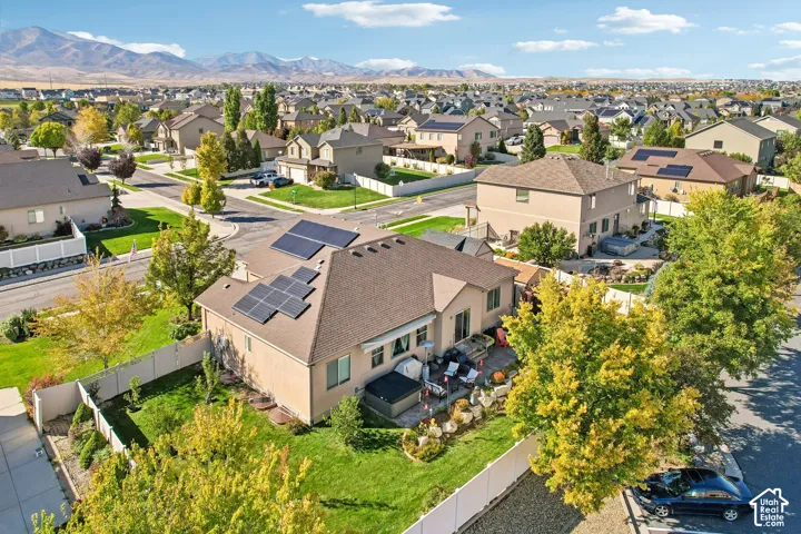 Rear property with solar panels, a manicured lawn, and a paved patio area