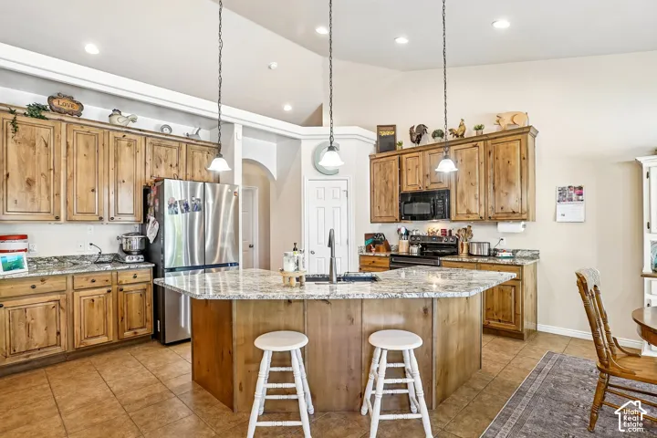 Kitchen featuring abundant wood cabinetry, granite-style countertops, stainless steel appliances, a center island with a sink, and recessed lighting