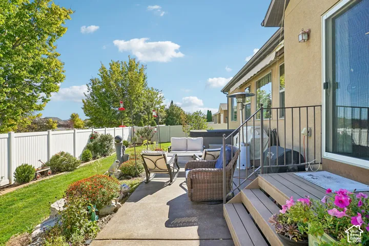 Backyard patio with concrete and composite wood decking, black metal railings, and a white privacy fence