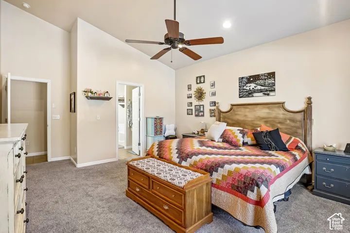 Vaulted ceiling with a ceiling fan, light neutral wall tones, and gray carpeting