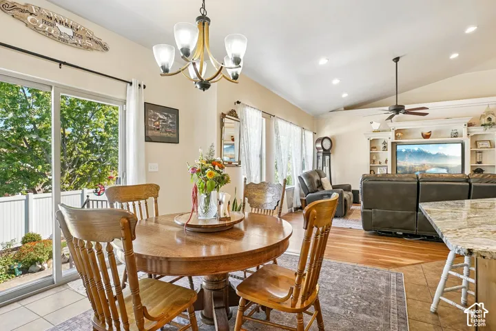 Vaulted ceiling with recessed lighting, wood-finish flooring, built-in shelving, sliding glass door, and a ceiling fan