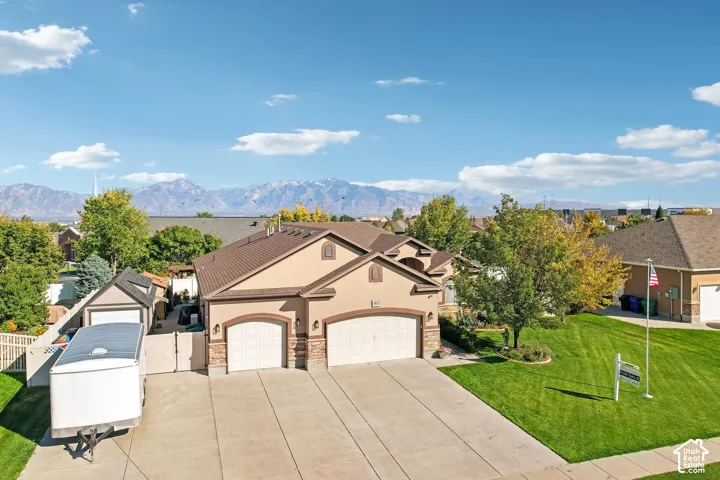 Stucco exterior with stone accents, two-car garage, concrete driveway, and a fenced yard with a gate