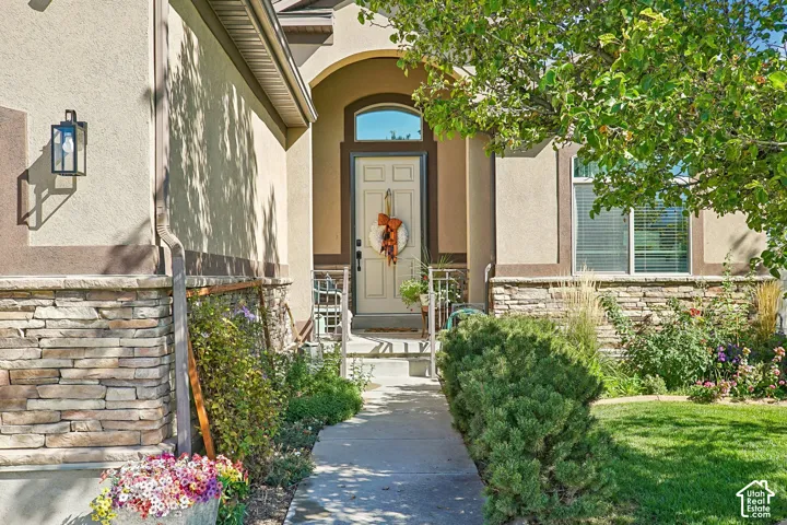 Stucco exterior with stone veneer accents, arched entry, transom window, and a concrete pathway
