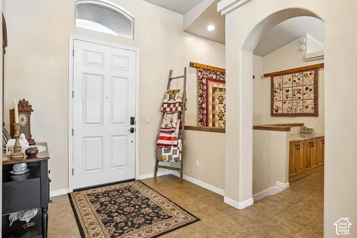 Arched doorway with a vaulted ceiling, transom window, and paneled entry door