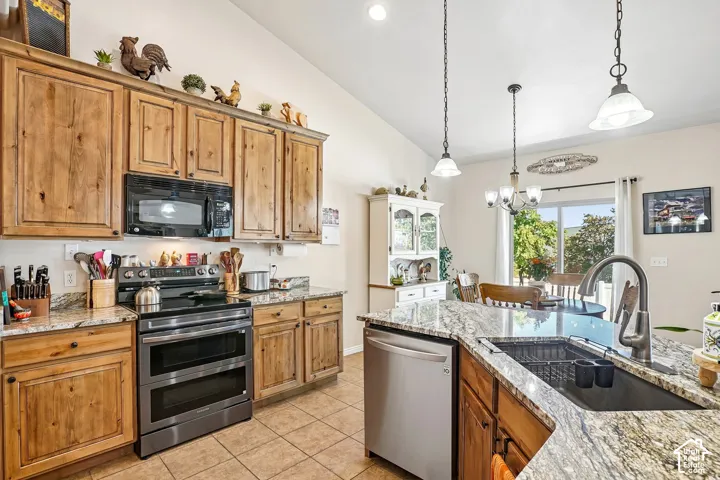 Kitchen featuring wood cabinetry, light-toned granite countertops, stainless steel appliances, and a tile floor