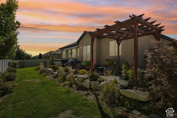 Expansive backyard featuring a manicured lawn, a rock garden, and a wooden pergola over a patio