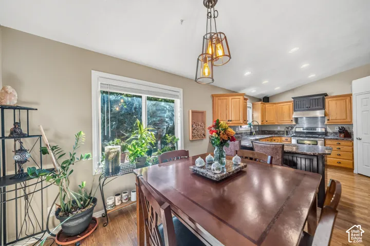Wood-finish flooring throughout, vaulted ceiling, recessed lighting, and a modern chandelier