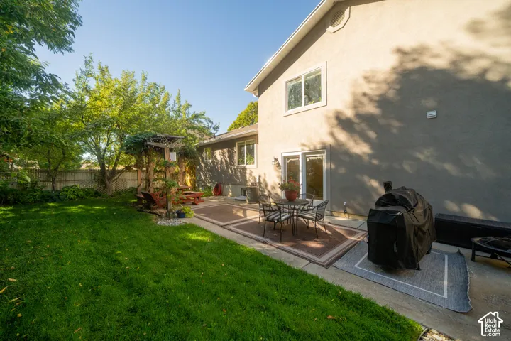 Expansive backyard featuring a manicured lawn, paved patio, and mature landscaping