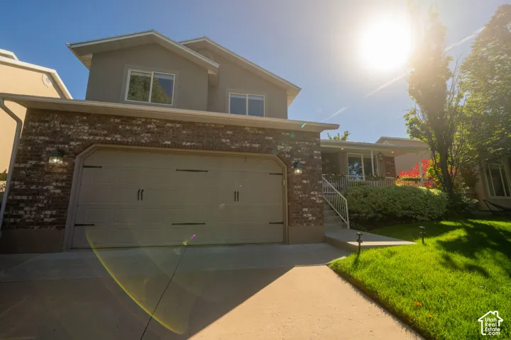 Stone and stucco exterior, two-car garage, concrete driveway, concrete walkway, and landscaped front yard