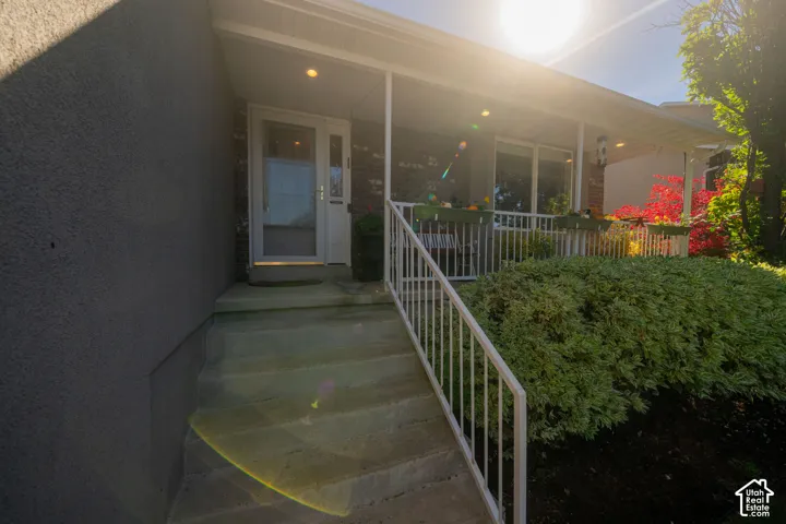 Covered front porch with recessed lighting, white railing, and brick accents