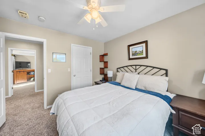 Carpeted flooring, ceiling fan with integrated lighting, and a white paneled door