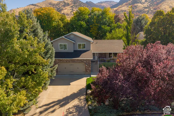 Traditional style residence featuring a two-car garage, covered entry, and mature landscaping